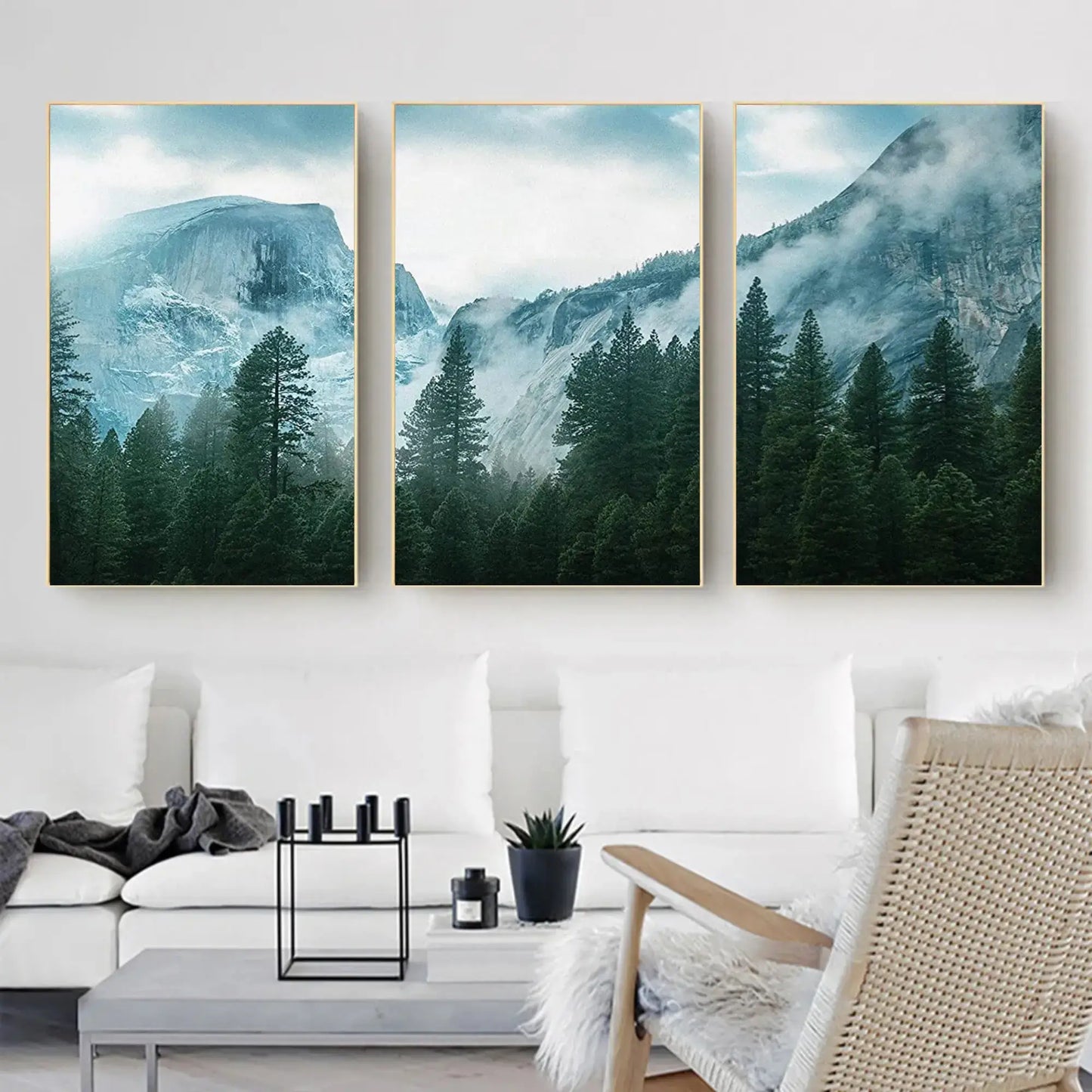 Three mountain landscape paintings above a white sofa in a living room.