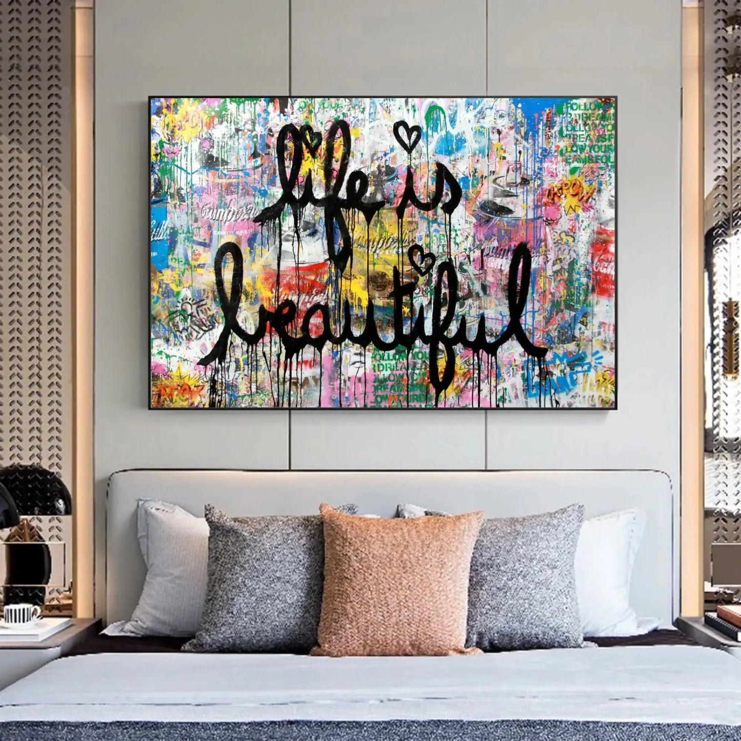 Colorful abstract painting with 'Life is Beautiful' text above a bed with decorative pillows.