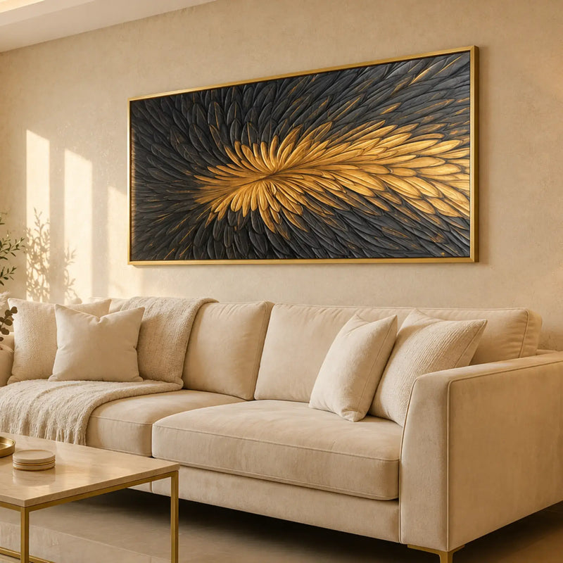 A large float frame wall art piece with a gold and black feather-like abstract design hangs above a beige sofa in a modern living room.