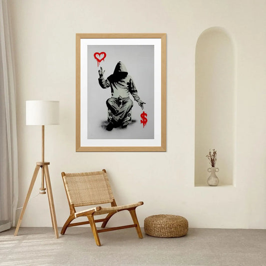 Framed artwork of a person with a heart and dollar sign on a wall in a room with a chair and lamp.